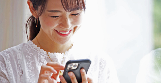 笑顔でスマホを見る女性